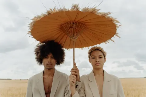 Two models under a straw parasol in a wheat field