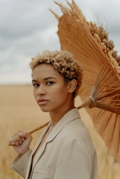 A model holding a straw parasol over her shoulder