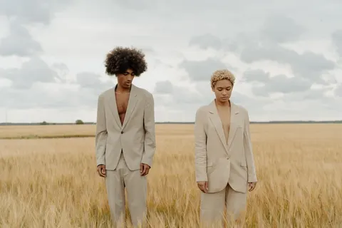 Two models in linen suits standing in a wheat field