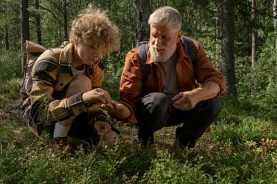 A man and a boy crouching to look at something in the moss
