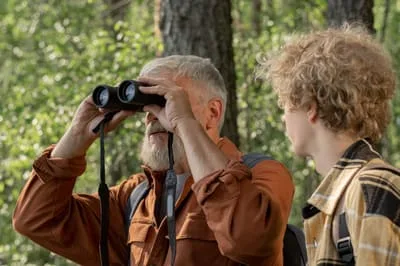 A man looking through binoculars beside a boy